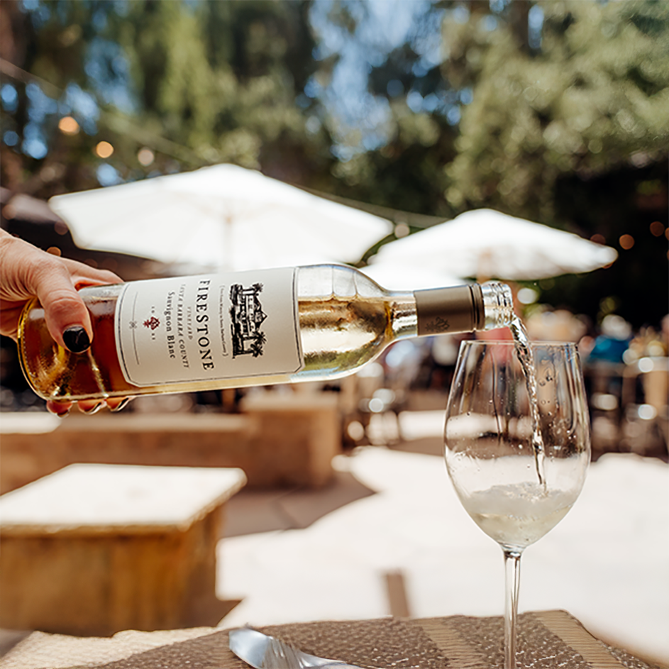 Outdoor wine pouring scene with white wine and relaxed patio gathering